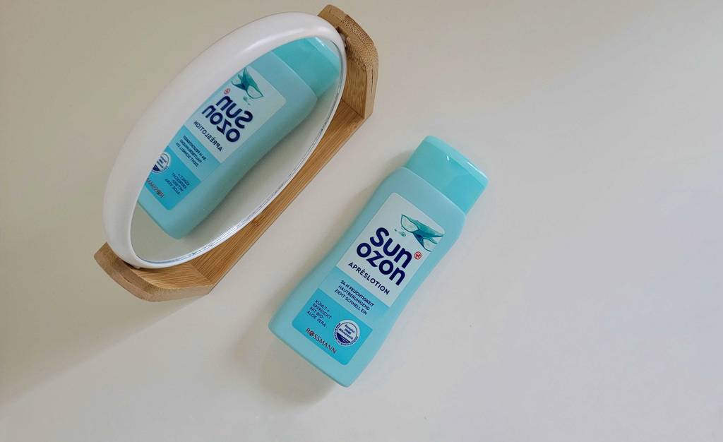 After-Sun getestet: Blaue After-Sun-Flasche liegend neben Komsetikspiegel.