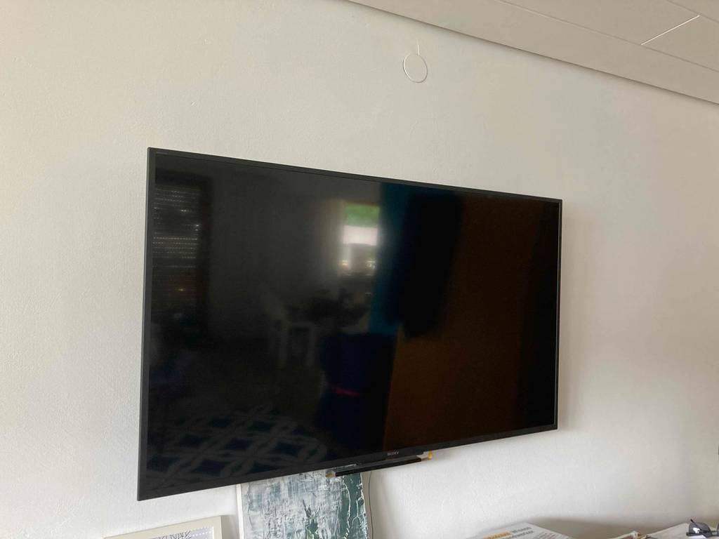 Im Test: Ein ausgeschalteter LED-Fernseher von schräg vorne an einer Wand moniert.