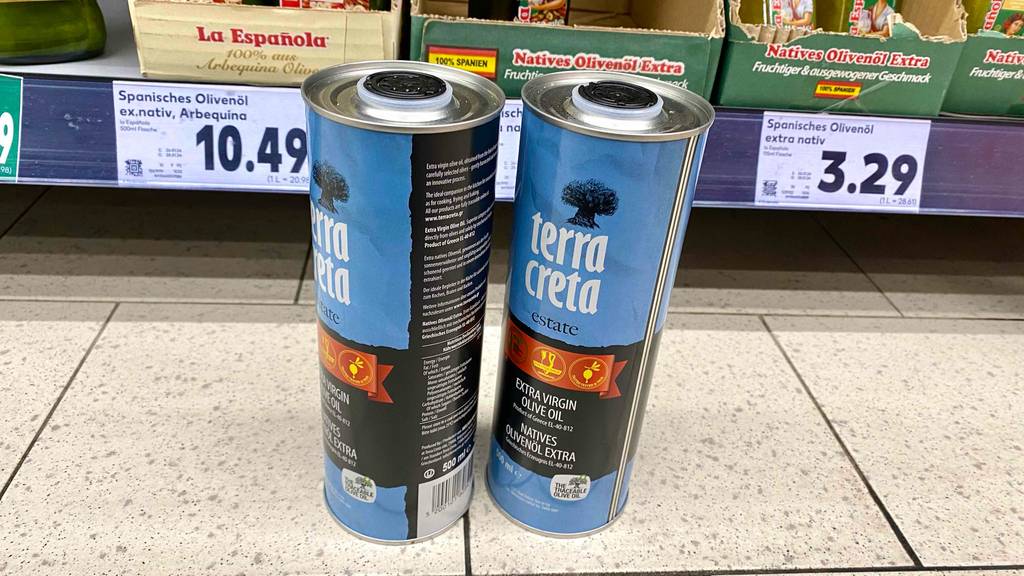 Zwei getestete Flaschen Terra-Creta-Olivenöl stehen vor einem Regal.