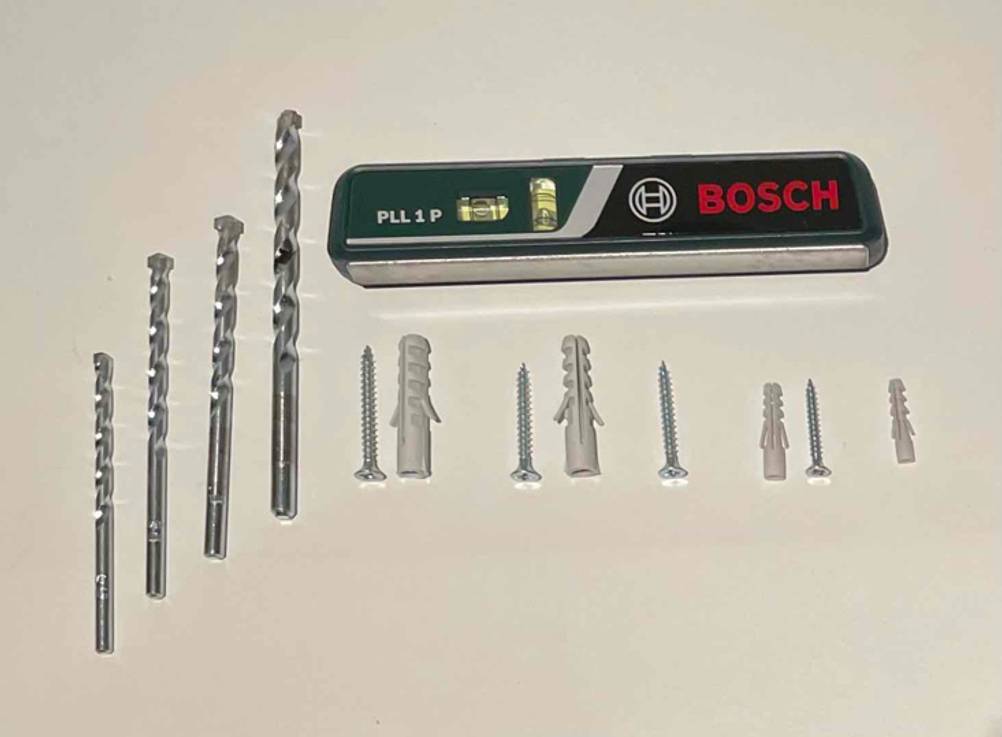 Bohrer-Set im Test: verschiedene Bohrer, Dübel und eine Bosch-Wasserwaage auf weißem Untergrund.