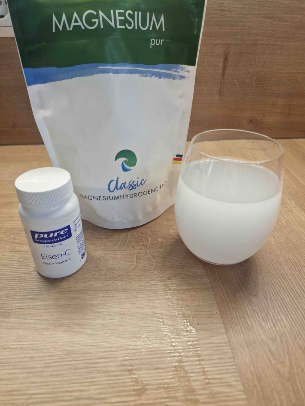 Magnesium Packung und ein Glas Wasser mit aufgelöstem Magnesium.