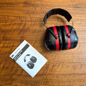 Der 3M Peltor Optime III liegt neben der Anleitung auf einem Tisch.