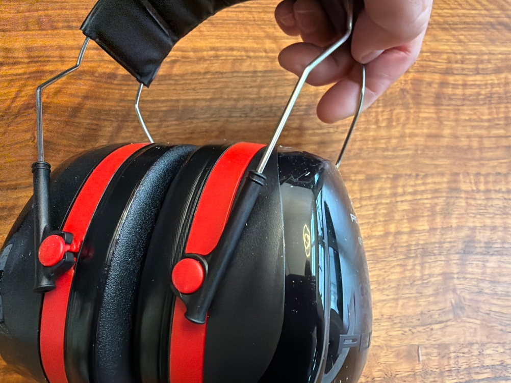 Eine Hand verlängert den Kopfbügel des 3M Peltor Optime III.