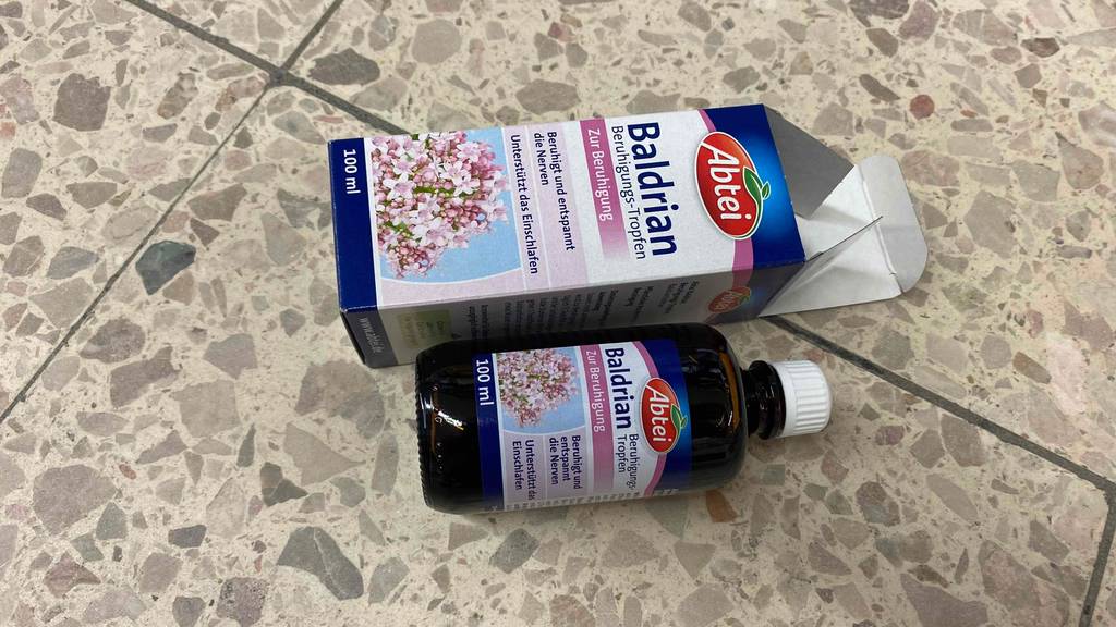 Eine getestete Flasche Baldrian liegt neben ihrer Verpackung auf einem Steinboden