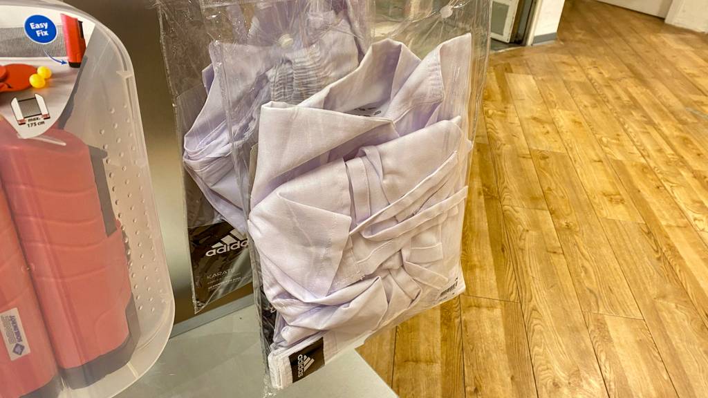 Karateanzug-Test: Adidas Karateanzug in Weiß hängt in einer Plastikverpackung in einem Geschäft.