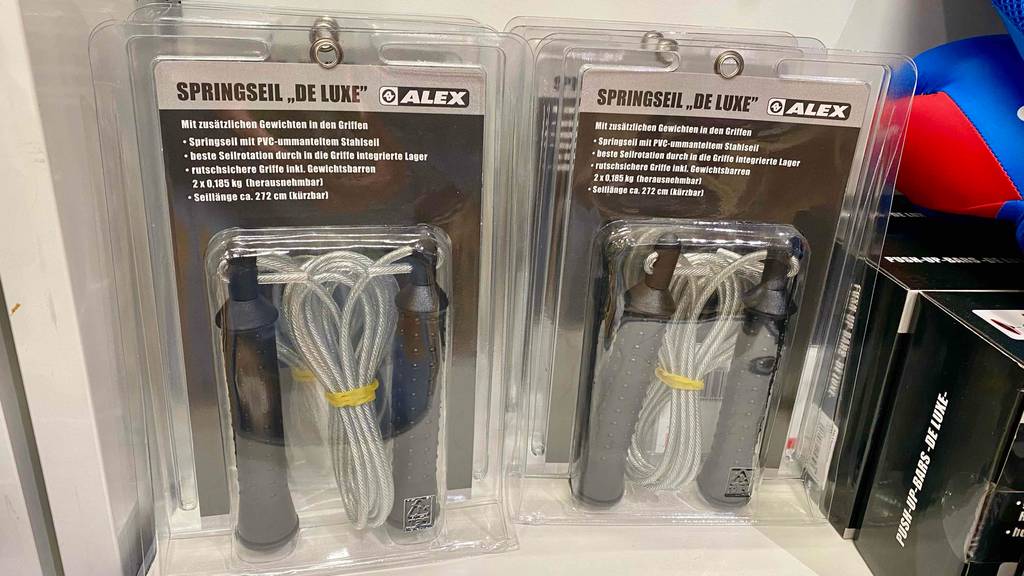 Springseil im Test: Springseile in Verpackungen mit zusätzlichen Gewichten in den Griffen hängen in einem Regal.