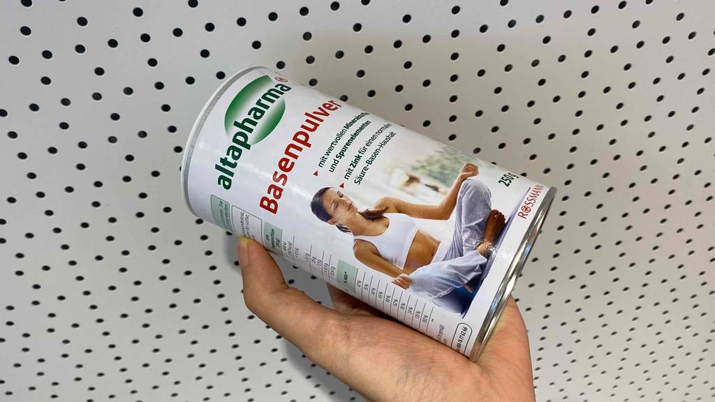 Basenpulver getestet: Basenpulver wird von vorn in der Hand gehalten - darauf eine meditierende Frau abgebildet.