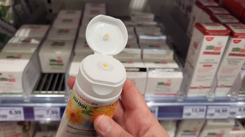 Ringelblumensalbe im Test: geöffnete Tube Ringelblumensalbe vor einem Regal.