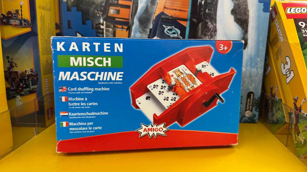 Die getestete Kartenmischmaschine mit Kurbel ab 3 Jahren steht in einem Regal neben Lego.