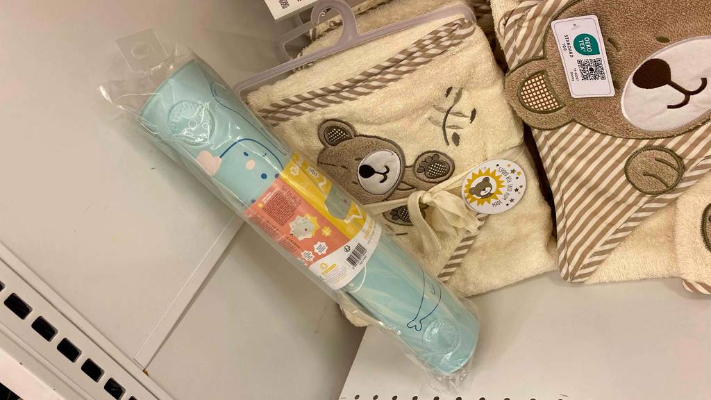 Badewannenmatte-Kinder im Test: Badewannenmatte für Kinder eingerollt in durchsichtiger Hülle vor Kinderhandtüchern.