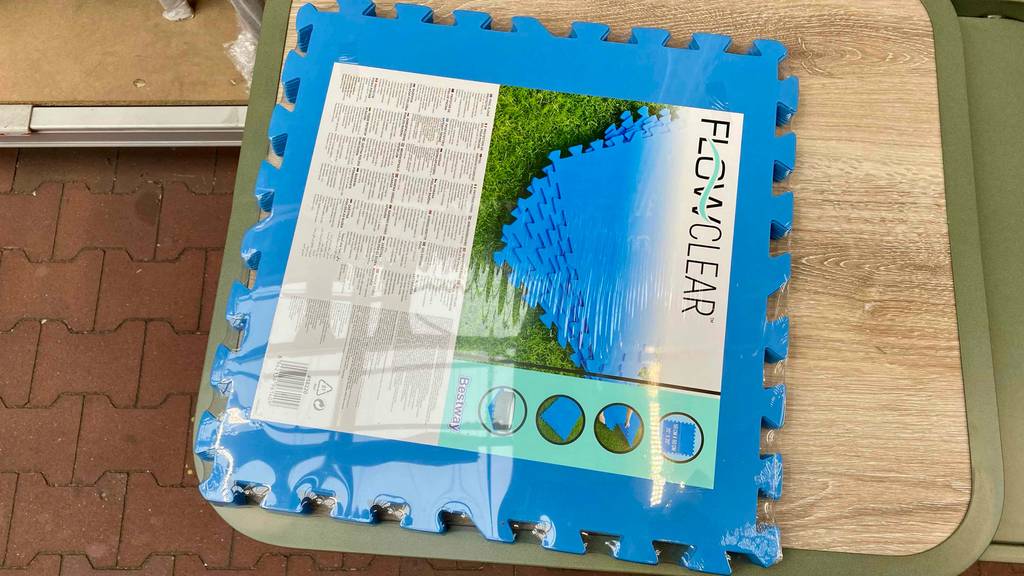 Bodenschutzmatte-Test: eine blaue Bodenschutzmatte, die zusammengesteckt werden kann, im liegenden Zustand in der Verpackung.