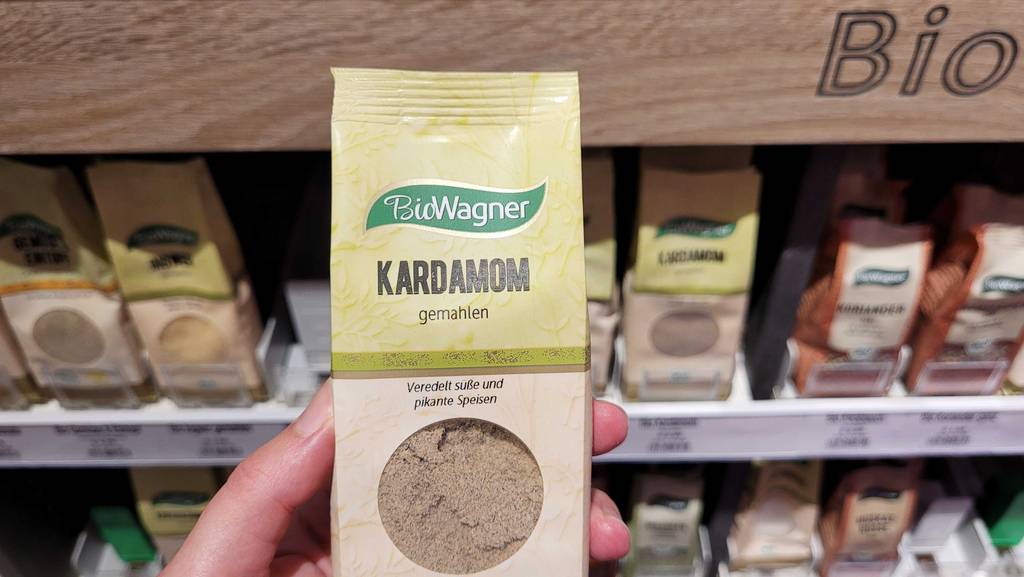 Kardamom-Test: Gemahlener Kardamom wird vor einem Regal gehalten.