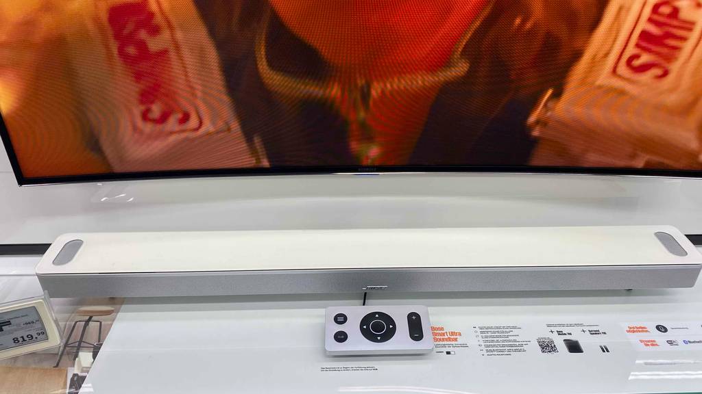 Im Test: Unter einem Fernseher steht eine Soundbar (weiß) auf einer hellen Fläche.