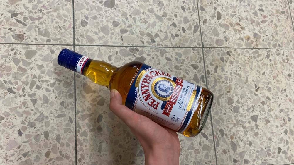 Im Test: Eine Hand hält eine Flasche Whisky vor einen hellen Boden
