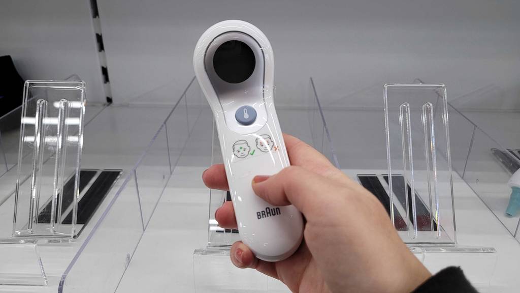 Getestet: Ein weißer, getesteter Stirnthermometer, der in der Hand gehalten wird.