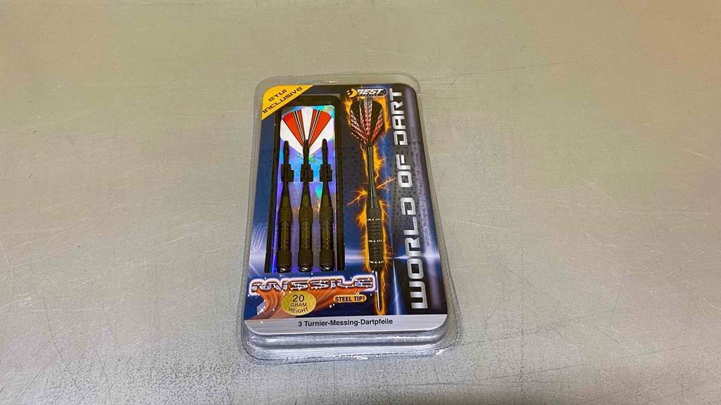 Steeldarts getestet: Eine Packung Steeldarts liegt auf einem grauen Boden.