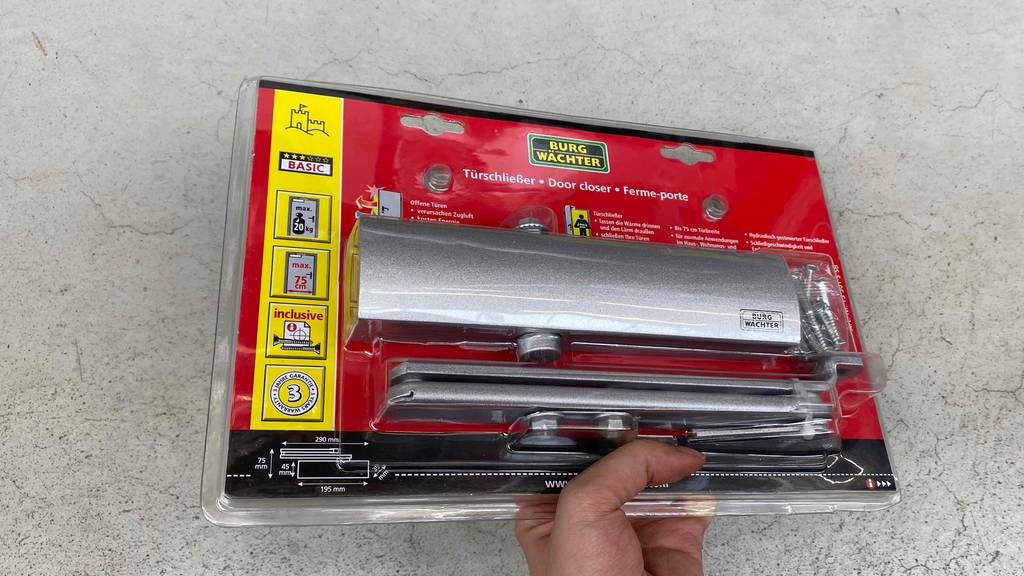 Türschließer im Test: silberner Türschließer in Verpackung wird in der Hand gehalten. 