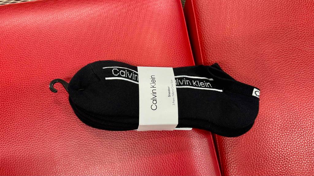 Die getesteten Herrensocken in Schwarz mit 3 Paar Socken in einem Pack liegen auf einem roten Hocker.
