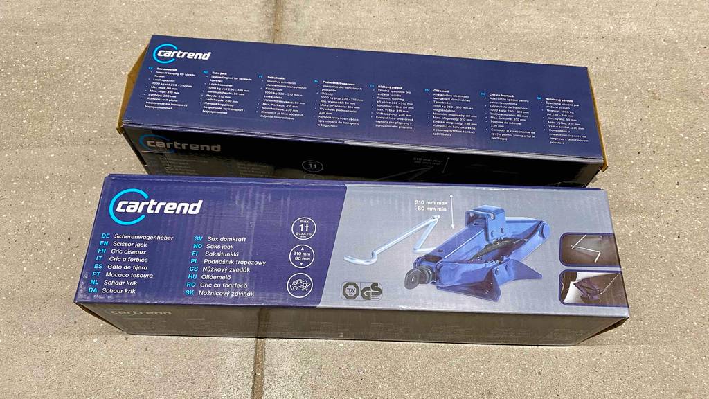 Im Test: Zwei verpackte Scherenwagenheber nebeneinander auf einem Betonboden.