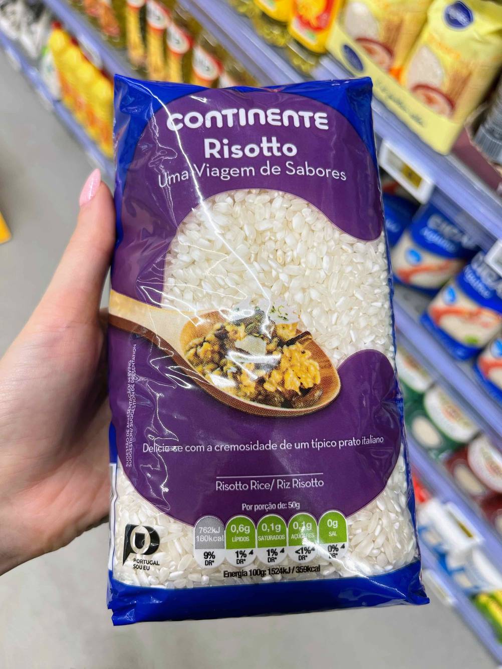 Risotto-Reis getestet: Eine Hand hält eine Packung Reis im Hintergrund Regal mit Produnkten