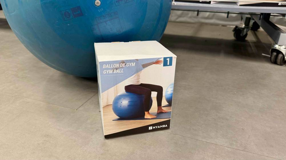 Die Verpackung des getesteten 65 cm Gymnastikballs steht vor dem blauen Gymnastikball.