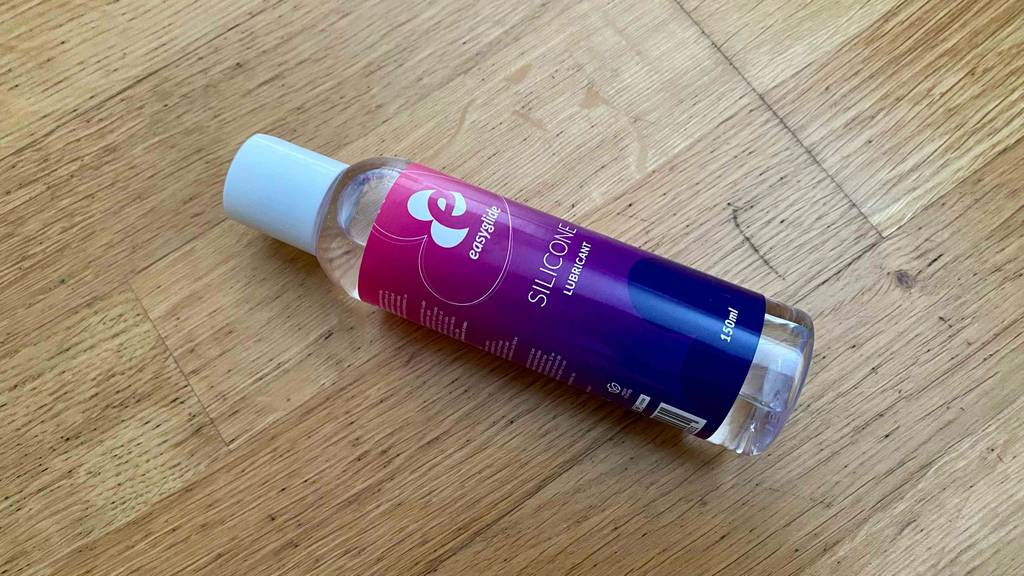 Im Test: Eine Flasche Silikon-Gleitgel quer auf einem Holzboden.