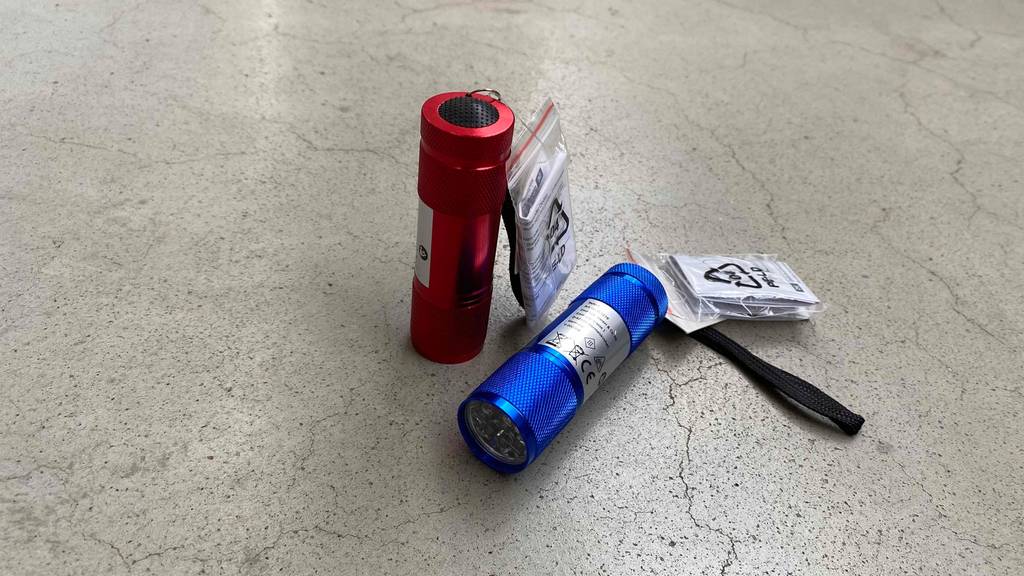 LED-Taschenlampe im Test: Rote und Blaue LED-Taschenlampe nebeneinander auf grauem Boden