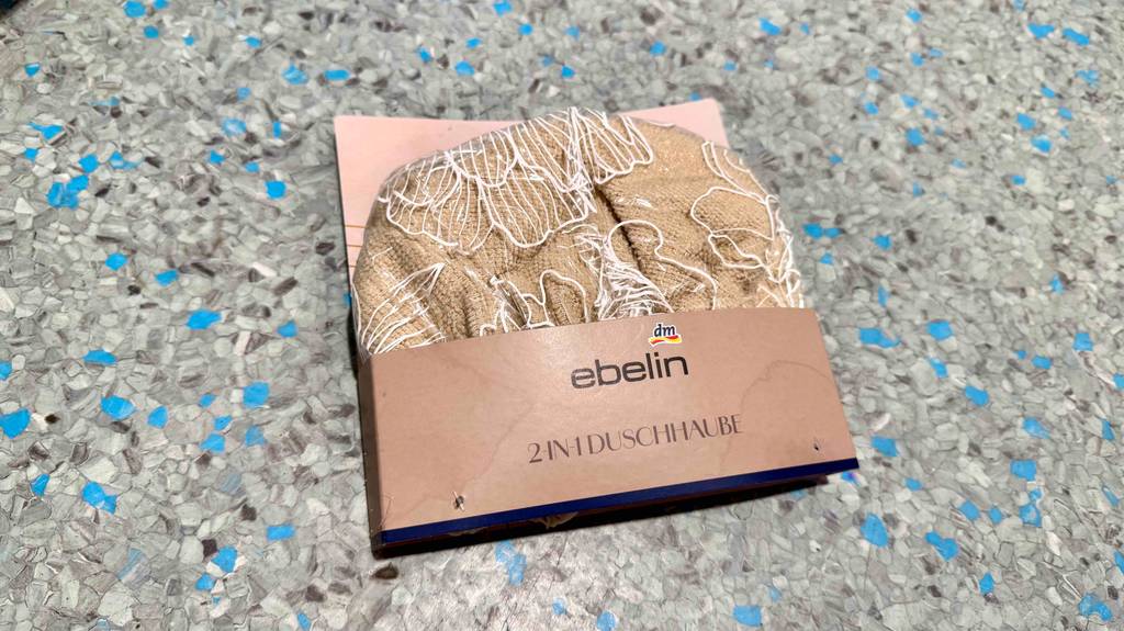 Eine 2-in-1-Duschhaube die getestet wurde liegt auf einem Boden in der Verpackung.