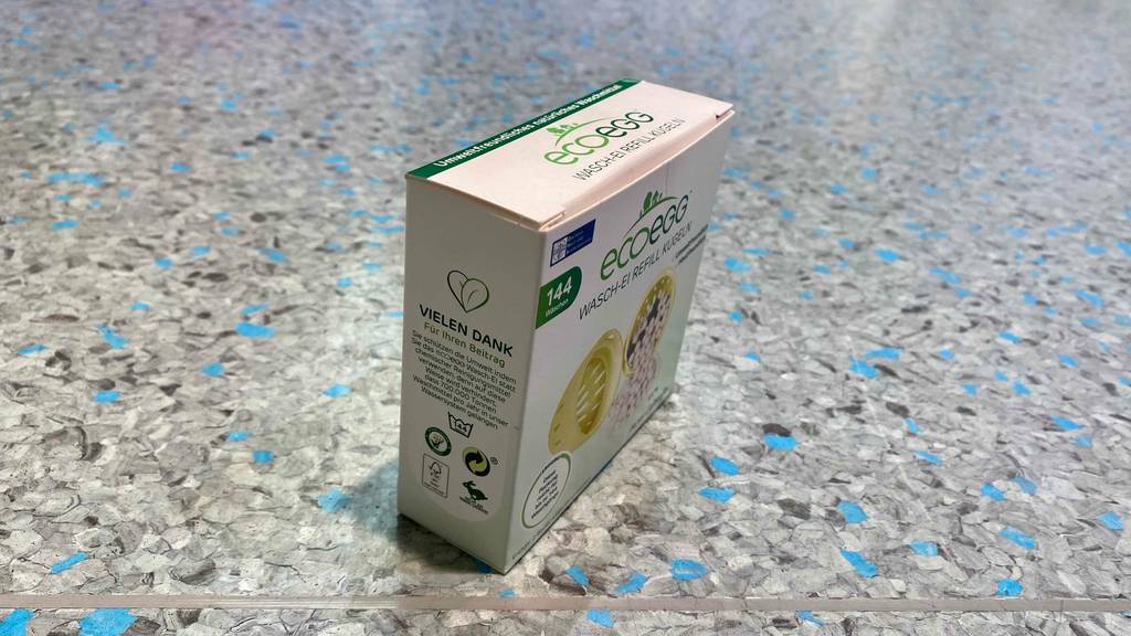 Im Test: Auf einem graublauen Boden steht eine verpackte Waschkugel.