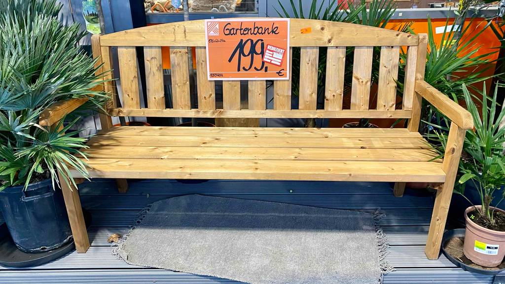Im Test: Eine Gartenbank (Holz) von vorne vor Pflanzen.