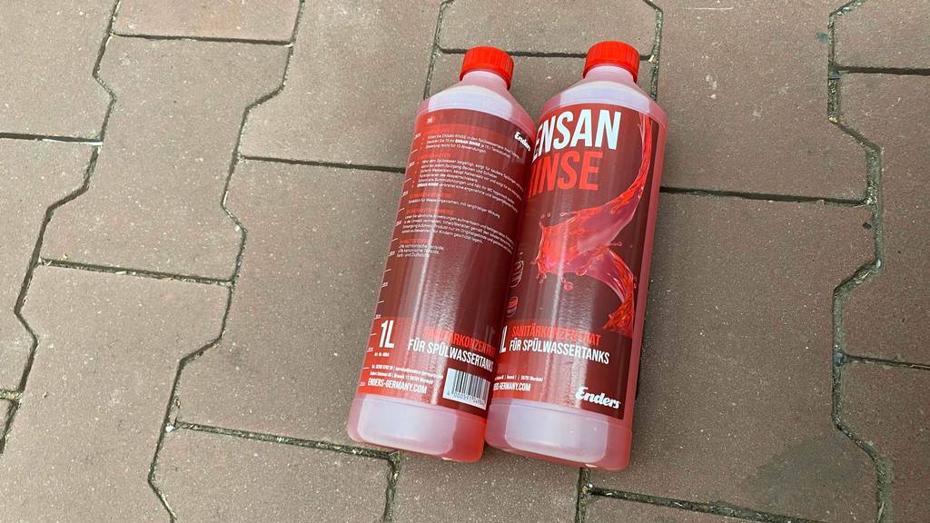 Im Test: Zwei Flaschen Sanitärflüssigkeit liegen nebeneinander auf einem Steinboden