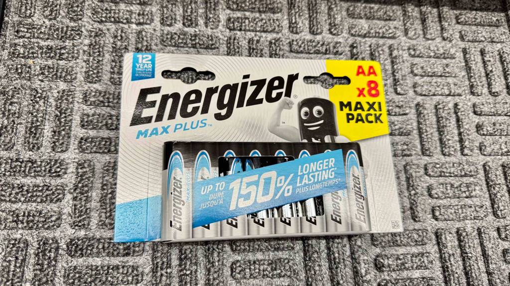 Getestete AA-Batterien mit einer Haltbarkeit von 12 Jahren auf einem Teppich liegen.