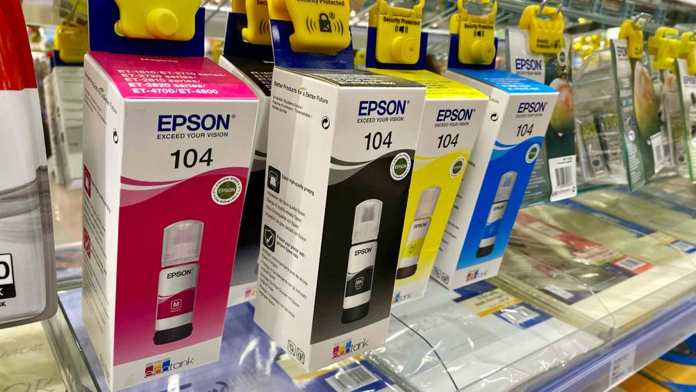 Mehrere getestete Epson-EcoTanks für A3-Drucker hängen nebeneinander im Regal.