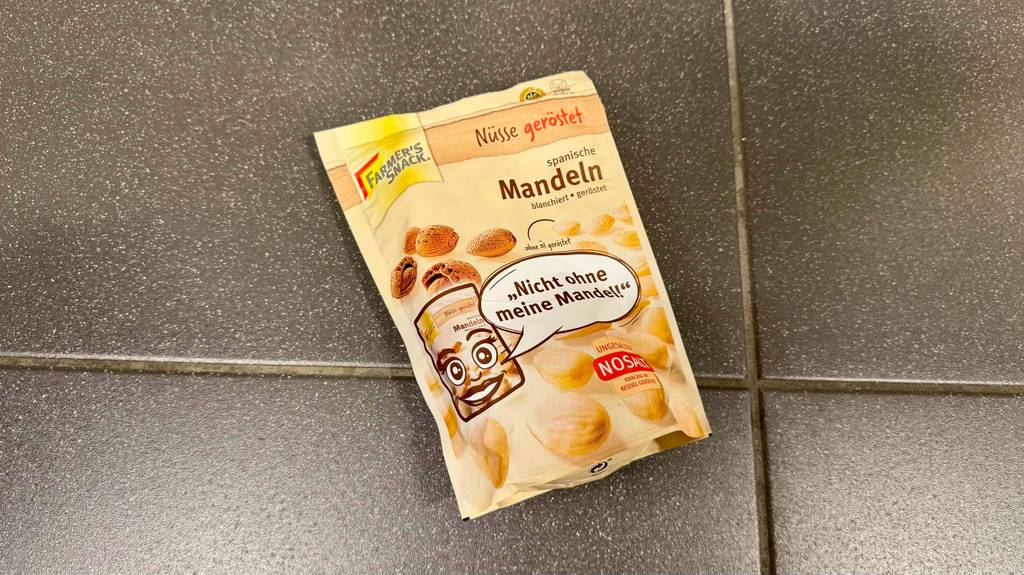 Eine Packung getestete Mandeln liegen auf einem grauen Boden.