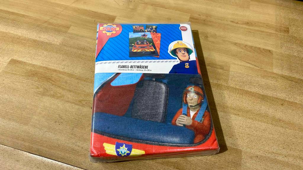 Auf einem Holzboden liegt verpackt eine getestete Flanell-Bettwäsche.