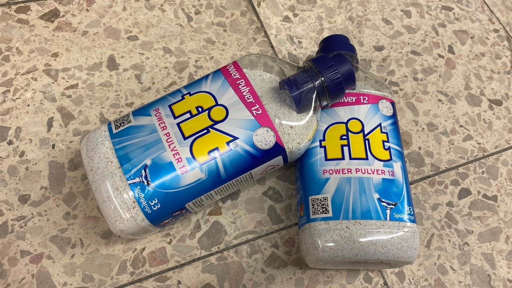 Spülmaschinenpulver getestet: Zwei Flaschen Spülmaschinenpulver liegen leicht übereinander auf dem Boden