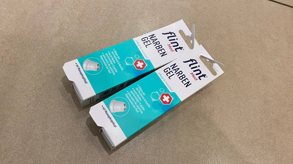 Narbengel getestet: Zwei Packungen nebeneinander auf einer beigen Fläche.