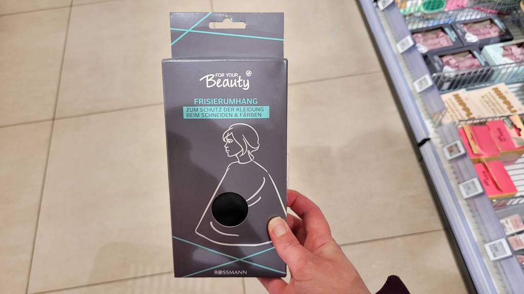 Der Friseurumhang welcher getestet wurde, wird in der hand gehalten.