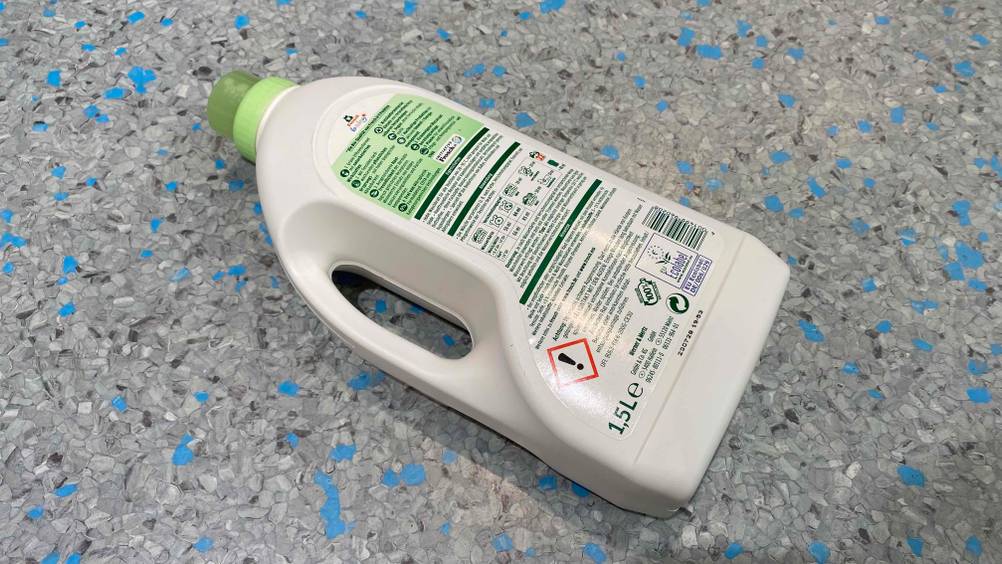 Baby Waschmittel getestet: Eine Flasche Waschmittel liegt mit der Rückseite nach oben auf einem Fließenboden
