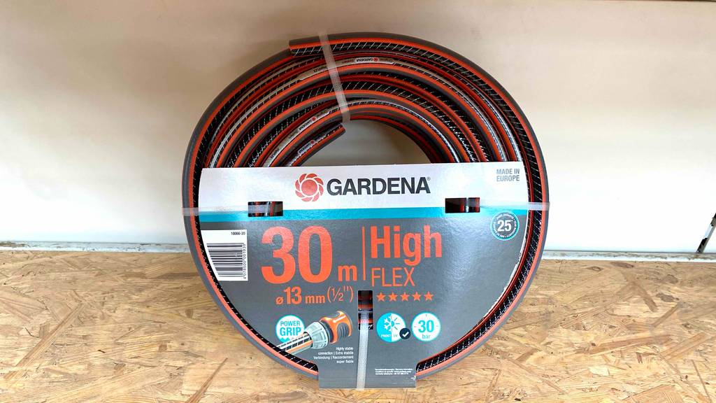 Flexibler-Gartenschlauch-30m getestet: Ein Gartenschlauch von Gardena mit einem Durchmesser von 13 mm ist an einer Regalrückwand angelehnt.