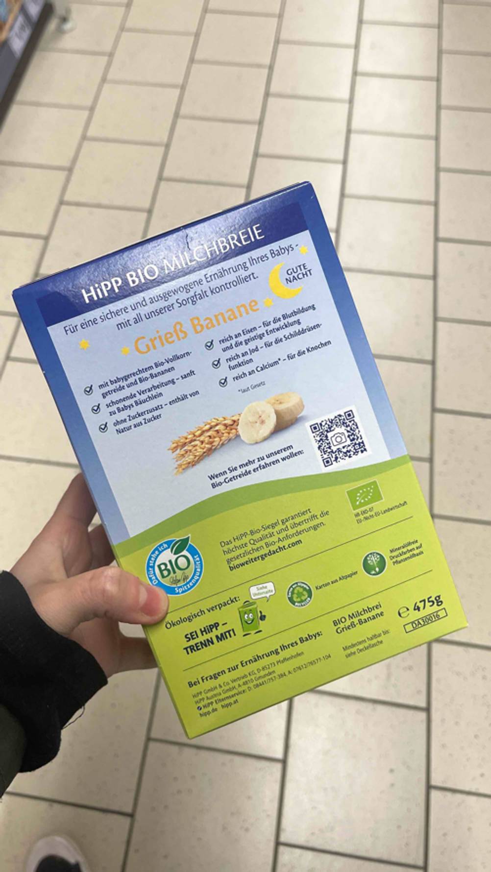 Getreide-Obst-Brei-Test: Die Rückseite des Grieß-Bananen-Breis in Bio-Qualität wird im Geschäft in der Hand gehalten.