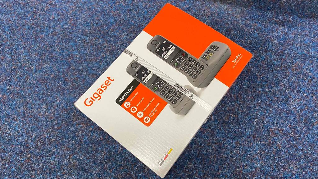 Schnurloses Telefon-Duo getestet: Eine Originalverpackung liegt quer auf einem blauen Teppichboden.