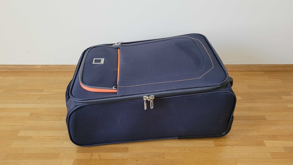 Ein getesteter Weichschalenkoffer von der Seite auf einer Holzfläche liegend.