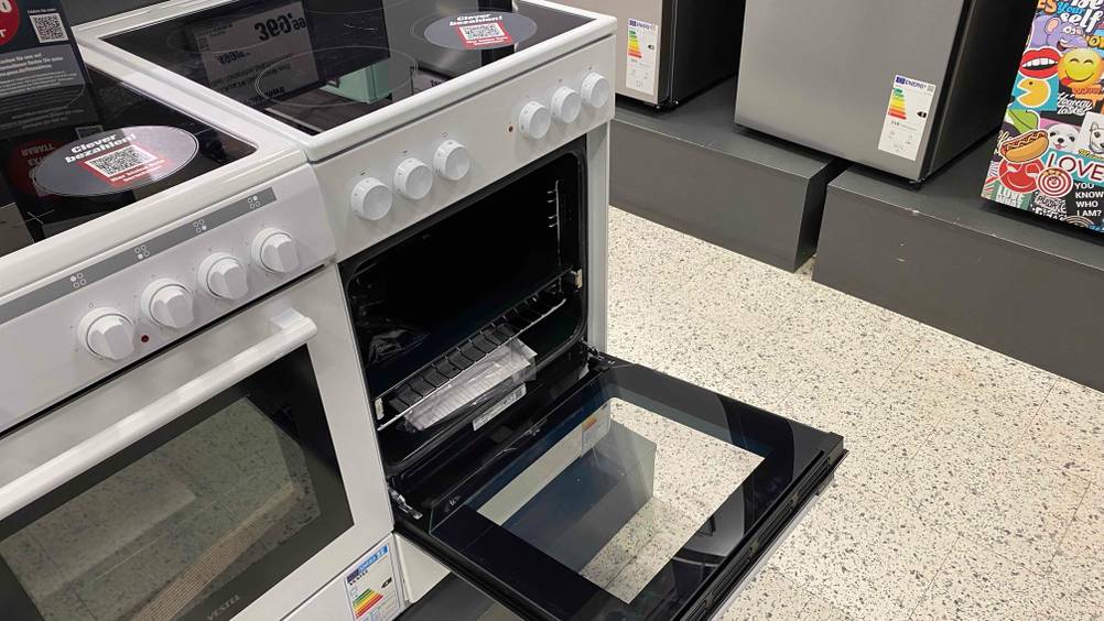 Im Test: Ein Elektroherd mit geöffneter Klappe schräg von der Seite neben anderen Produkten.
