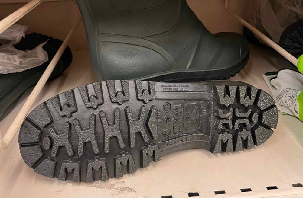 Gummistiefel-Herre-Test: ein Paar Gummistiefel in einem Regal - von einem ist die Sohle zu sehen und der andere stehend.