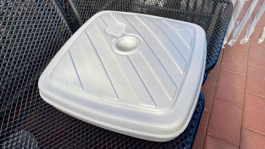 Schirmständer-Test: ein weißer Schirmständer ist auf schwarzen Stühlen platziert.