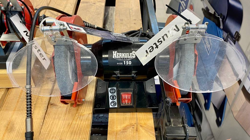 Doppelschleifer im Test: Doppelschleifer mit rotem Ein- und Ausschalter und daneben Hinweise, welche Sicherheitsvorkehrungen getroffen werden sollten.