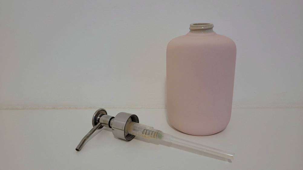 Seifenspender getestet: Eine Flasche vor einer hellen Wand, davor liegt der Spenderkopf.