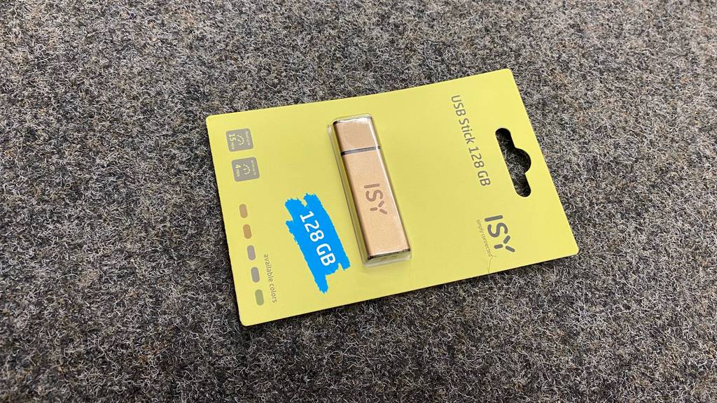 Ein getesteter USB-Stick (128 GB) liegt quer auf einem dunklen Teppich.