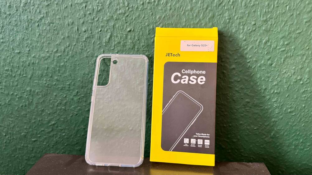 Die getestete Samsung-Galaxy-S22-Plus-Hülle lehnt neben der Verpackung an einer grünen Wand.